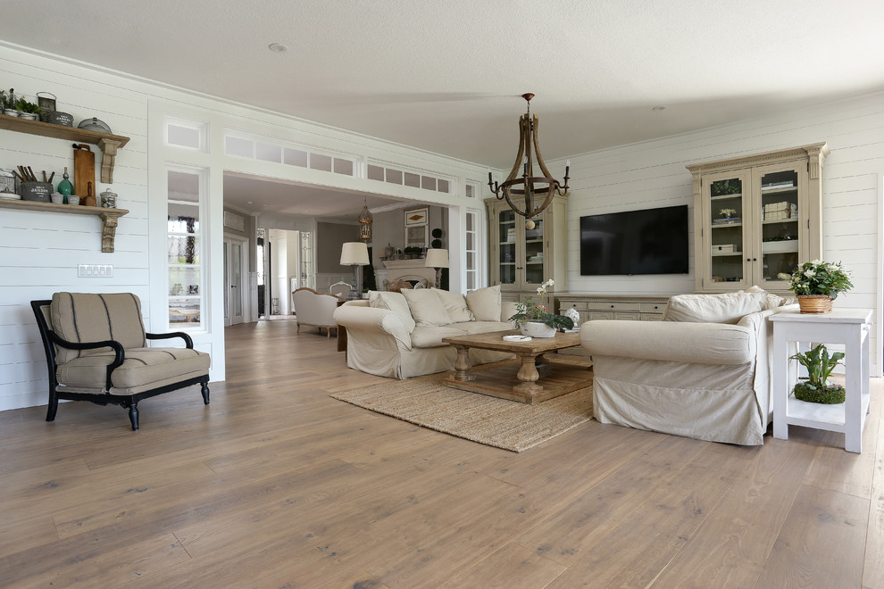 Photo of a mid-sized beach style open concept family room in Denver with white walls, no fireplace, a wall-mounted tv, brown floor and medium hardwood floors.