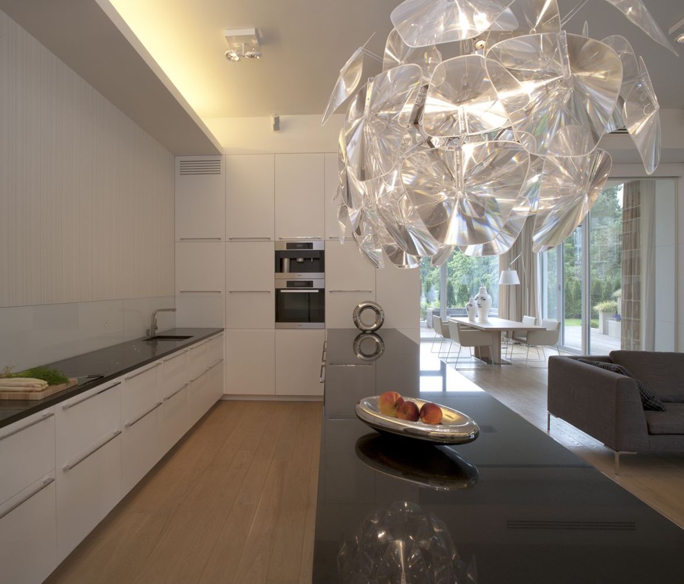 Photo of a contemporary u-shaped open plan kitchen with flat-panel cabinets, white cabinets and white splashback.