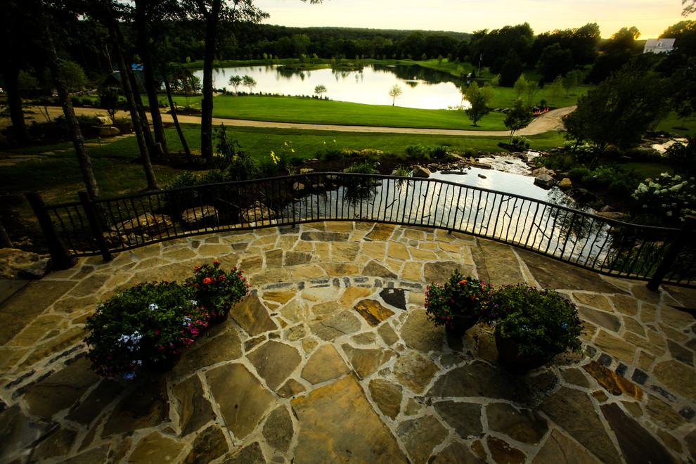 This is an example of a country backyard shaded garden for summer in St Louis with natural stone pavers.