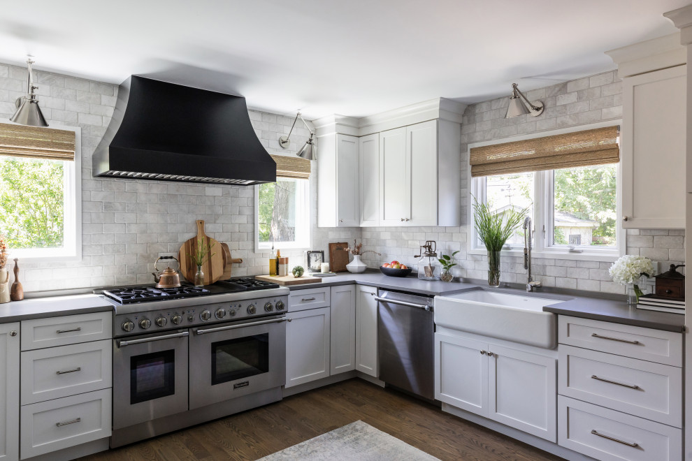 Mid-sized transitional u-shaped medium tone wood floor and brown floor open concept kitchen photo in Chicago with a farmhouse sink, shaker cabinets, white cabinets, quartz countertops, white backsplash, marble backsplash, stainless steel appliances, an island and gray countertops