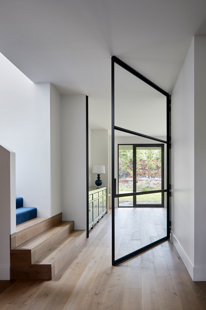 Photo of an expansive contemporary hallway in Melbourne with white walls, light hardwood floors and brown floor.