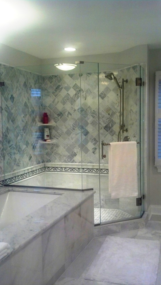 Photo of a large traditional master bathroom in DC Metro with an undermount sink, raised-panel cabinets, white cabinets, marble benchtops, an undermount tub, a shower/bathtub combo, a two-piece toilet, white tile, stone slab, grey walls and marble floors.