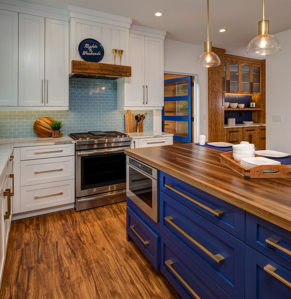This is an example of a mid-sized transitional l-shaped eat-in kitchen in Other with an undermount sink, shaker cabinets, white cabinets, quartz benchtops, blue splashback, glass tile splashback, panelled appliances, medium hardwood floors, with island, brown floor and white benchtop.