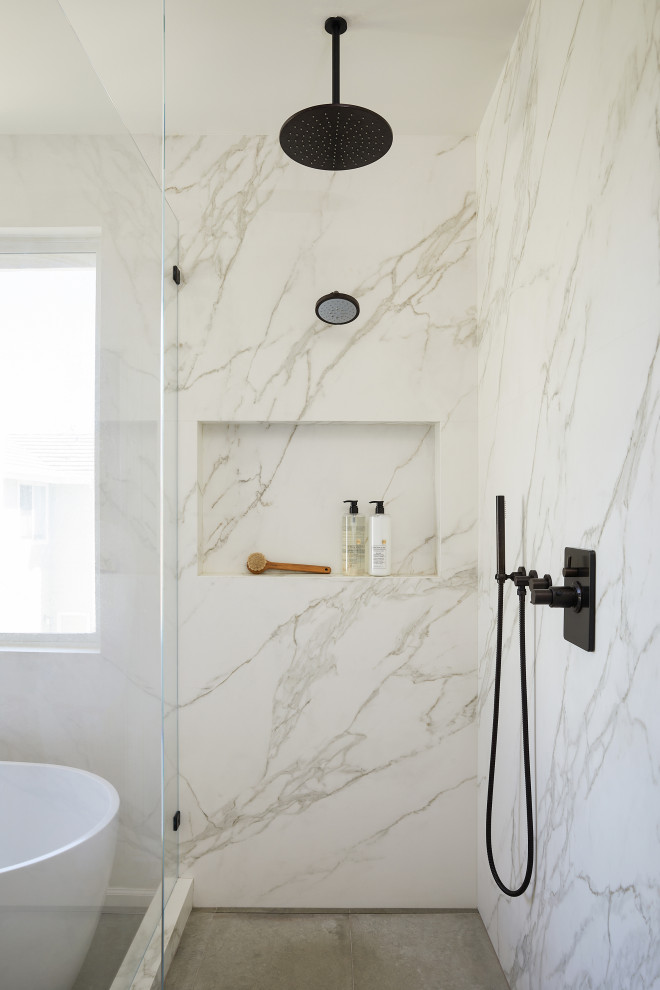 Design ideas for a large contemporary master bathroom in San Francisco with furniture-like cabinets, light wood cabinets, a freestanding tub, a corner shower, a two-piece toilet, beige tile, ceramic tile, white walls, limestone floors, an undermount sink, marble benchtops, grey floor, a hinged shower door, purple benchtops, an enclosed toilet, a double vanity and a built-in vanity.