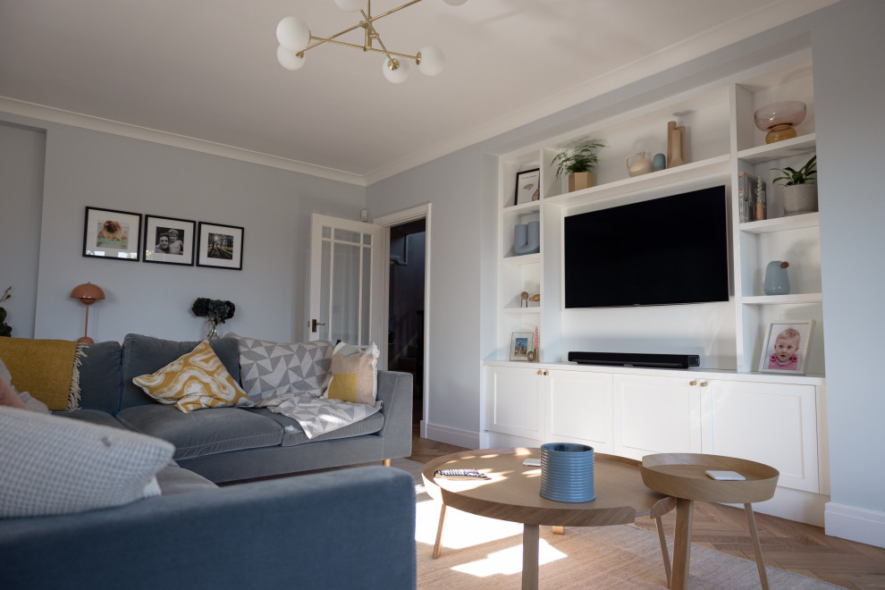 Exemple d'un grand salon tendance ouvert avec un mur bleu, parquet clair, un téléviseur encastré, un sol marron, du papier peint et éclairage.