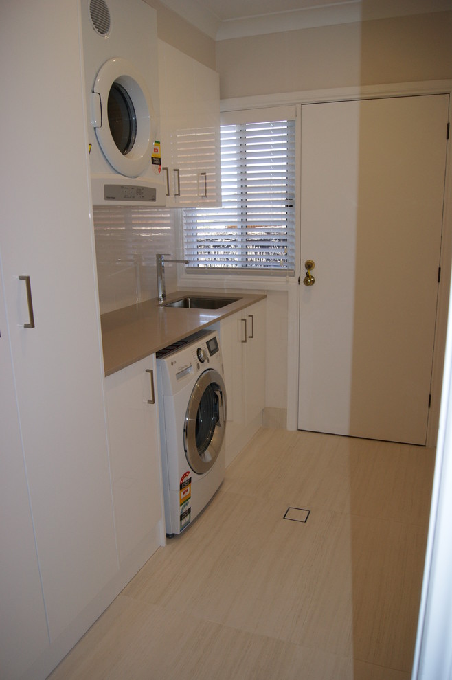 Inspiration for a mid-sized contemporary galley dedicated laundry room in Sydney with an undermount sink, flat-panel cabinets, white cabinets, quartz benchtops and porcelain floors.