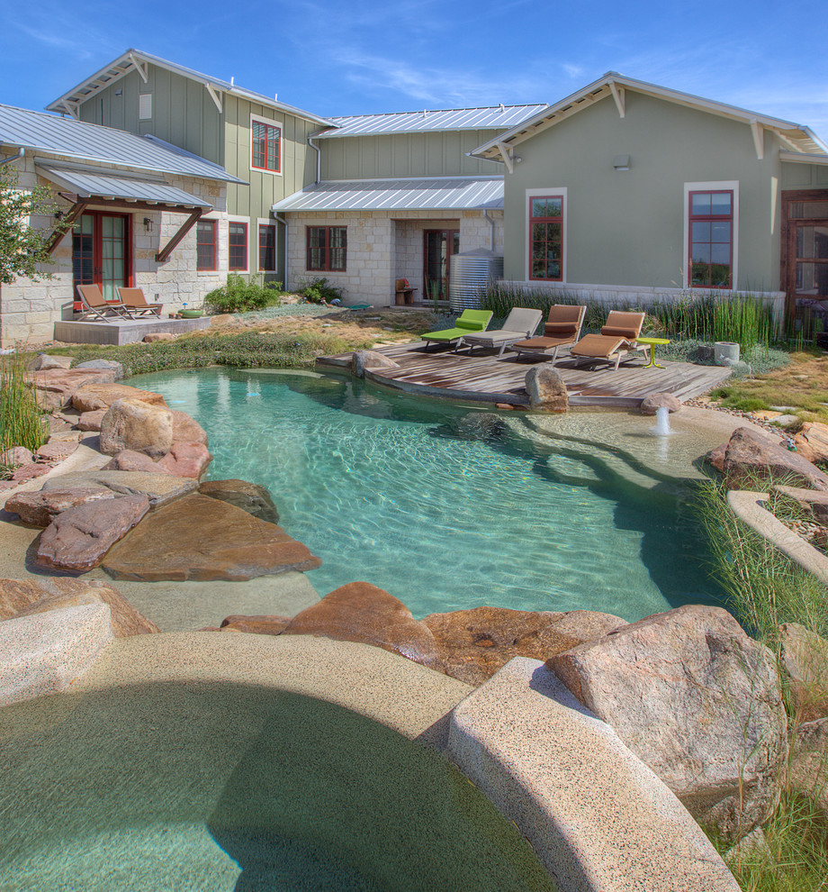 Photo of a country custom-shaped natural pool in Austin with natural stone pavers.