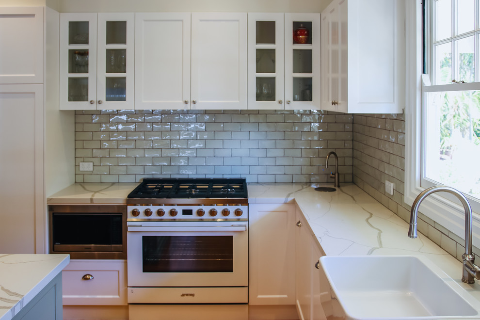 Design ideas for a large traditional l-shaped eat-in kitchen in Brisbane with a farmhouse sink, shaker cabinets, green cabinets, quartz benchtops, green splashback, subway tile splashback, white appliances, medium hardwood floors, with island and green benchtop.