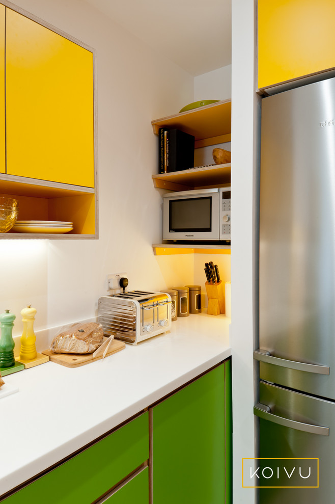 Design ideas for a small contemporary l-shaped eat-in kitchen in Kent with an integrated sink, flat-panel cabinets, yellow cabinets, solid surface benchtops, white splashback, glass sheet splashback, stainless steel appliances, light hardwood floors, no island and white benchtop.