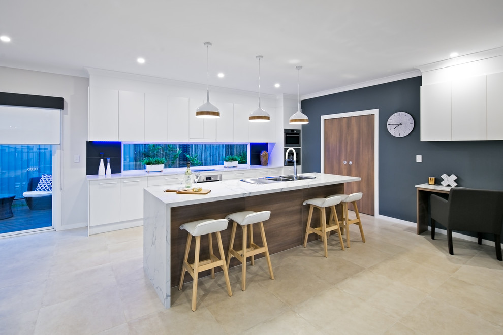 Inspiration for a large contemporary galley open plan kitchen in Brisbane with a double-bowl sink, white cabinets, quartz benchtops, grey splashback, porcelain splashback, stainless steel appliances, porcelain floors, with island and beige floor.