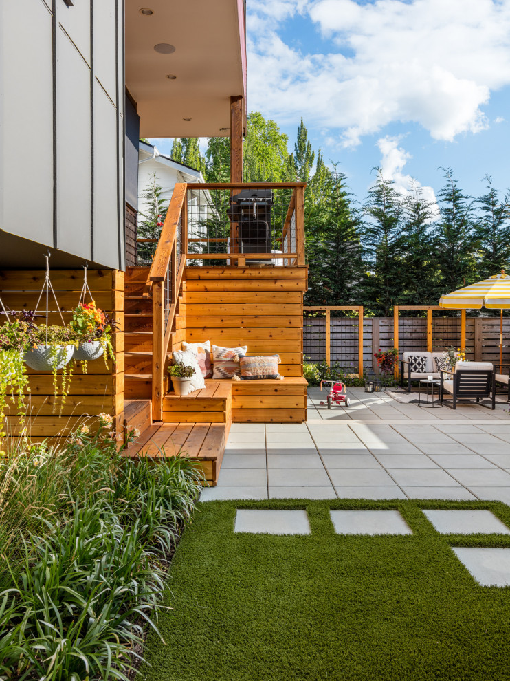 Cette image montre un petit jardin arrière design avec une exposition ensoleillée, des pavés en béton et une clôture en bois.