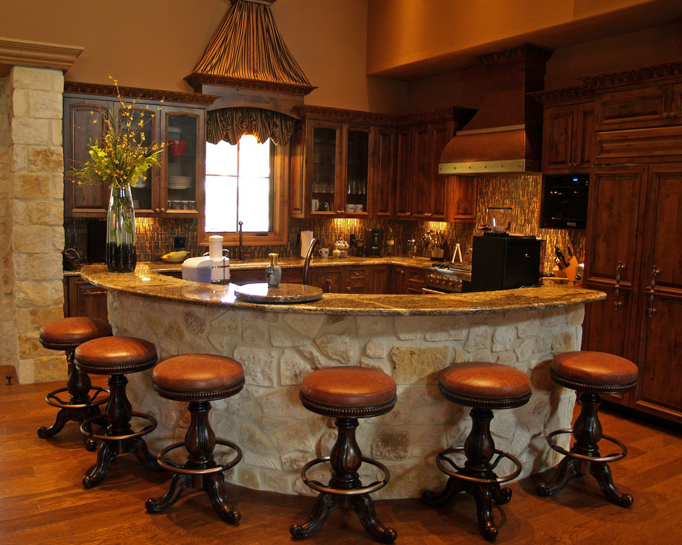 Open concept kitchen - transitional l-shaped medium tone wood floor open concept kitchen idea in Austin with raised-panel cabinets, medium tone wood cabinets, granite countertops, multicolored backsplash, glass tile backsplash, paneled appliances and an island