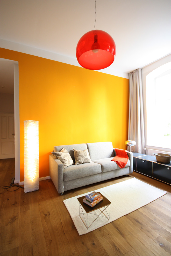 Design ideas for a small contemporary family room in Berlin with yellow walls and medium hardwood floors.