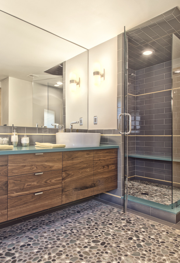 Design ideas for a mid-sized midcentury master bathroom in Detroit with a vessel sink, flat-panel cabinets, medium wood cabinets, engineered quartz benchtops, gray tile, subway tile and pebble tile floors.