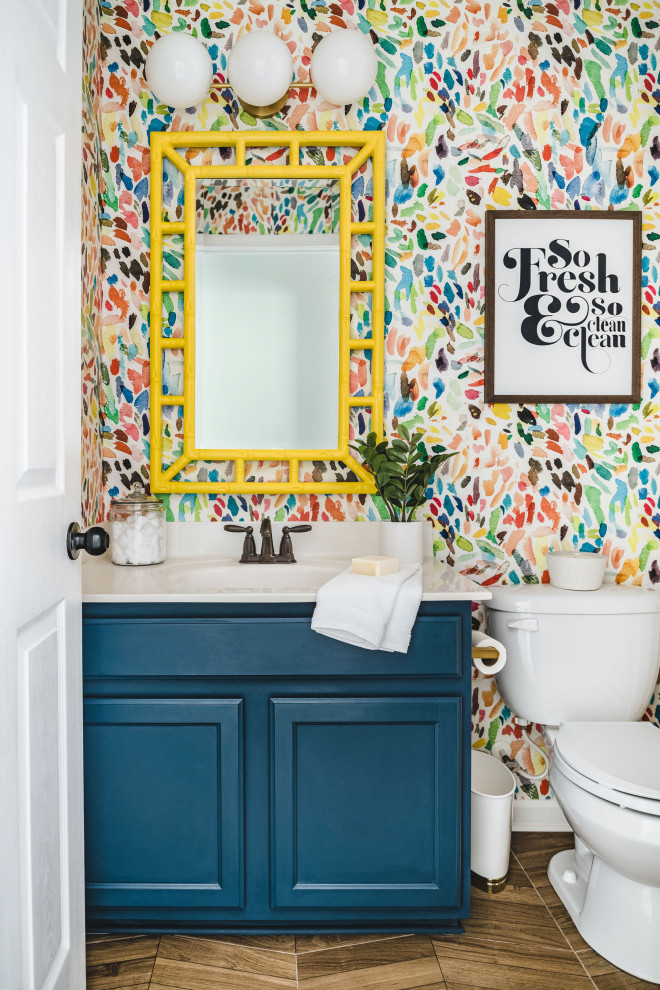 Klassisk inredning av ett litet vit vitt toalett, med luckor med infälld panel, blå skåp, en toalettstol med separat cisternkåpa, flerfärgade väggar, ett integrerad handfat, bänkskiva i kvarts och brunt golv