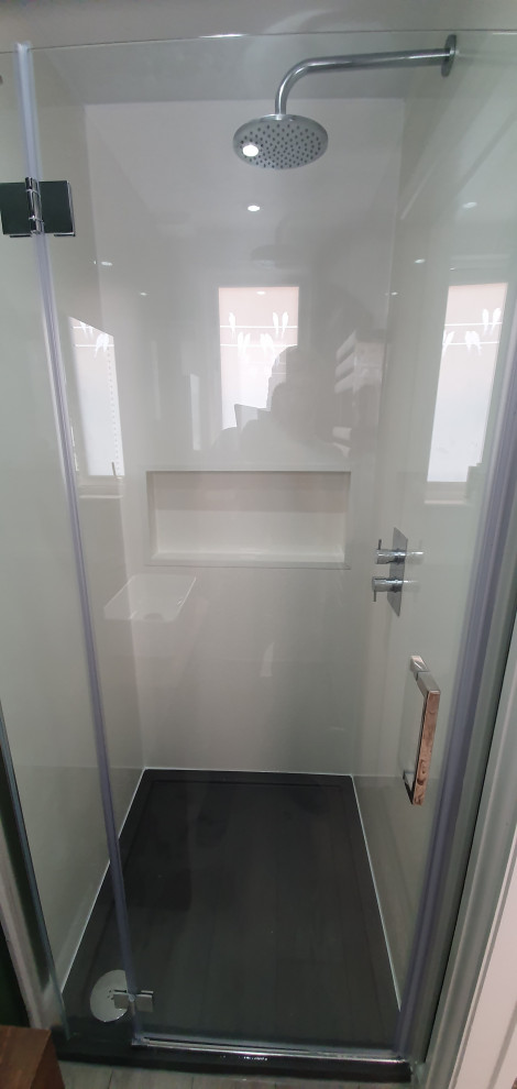 This is an example of a small contemporary bathroom in Surrey with flat-panel cabinets, white cabinets, an open shower, a one-piece toilet, green walls, laminate floors, a trough sink, wood benchtops, grey floor, a hinged shower door, brown benchtops, a single vanity and a built-in vanity.
