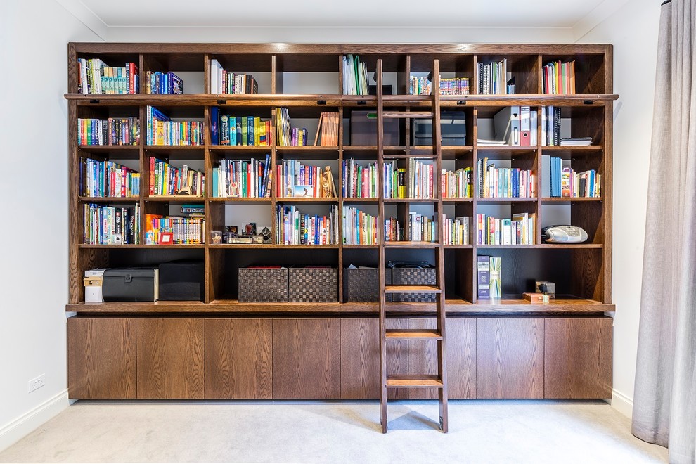 Photo of a mid-sized contemporary home office in Melbourne with a library, white walls, carpet, no fireplace and beige floor.