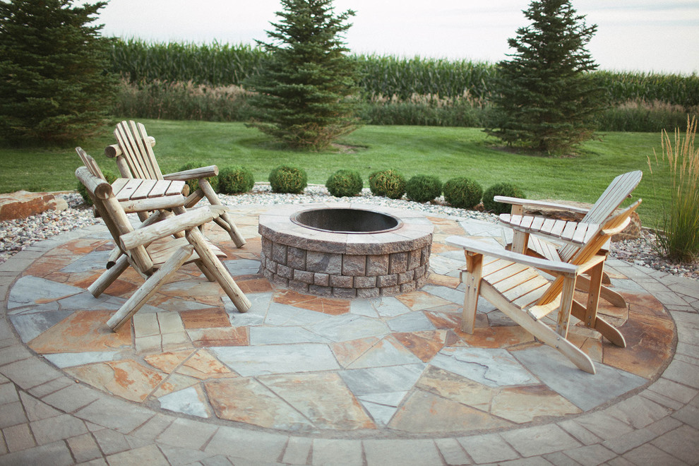 Example of a mountain style stone patio design with a fire pit and no cover