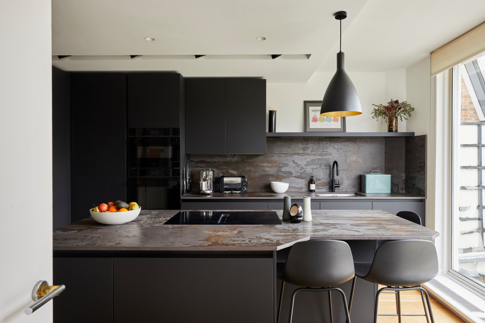 Modern inredning av ett avskilt, litet flerfärgad flerfärgat l-kök, med en undermonterad diskho, släta luckor, bänkskiva i kvarts, flerfärgad stänkskydd, svarta vitvaror, ljust trägolv, en köksö, svarta skåp och beiget golv