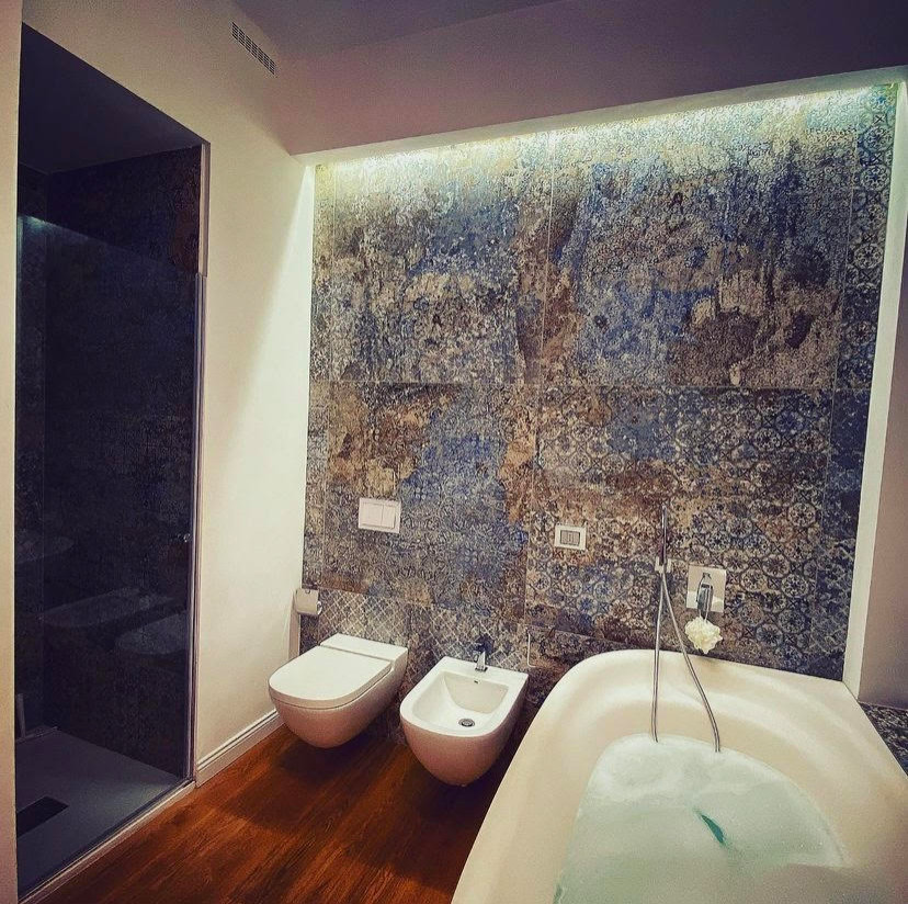 Inspiration for a 3/4 wet room bathroom in Milan with white cabinets, a wall-mount toilet, multi-coloured tile, porcelain tile, white walls, dark hardwood floors and a hinged shower door.