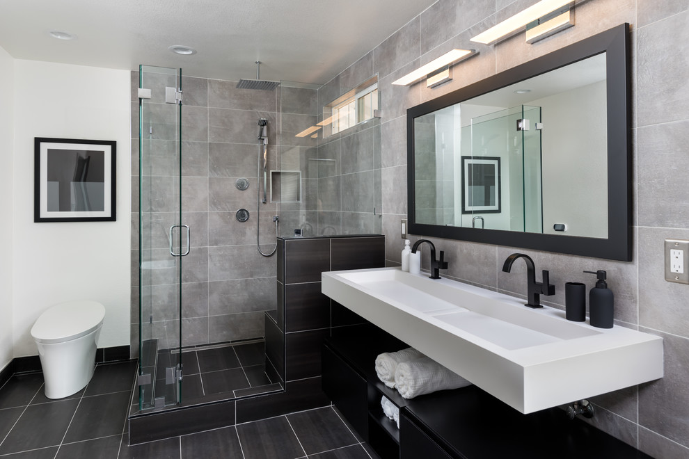 Design ideas for a contemporary bathroom in San Francisco with flat-panel cabinets, black cabinets, a corner shower, white walls, a trough sink, black floor and a hinged shower door.