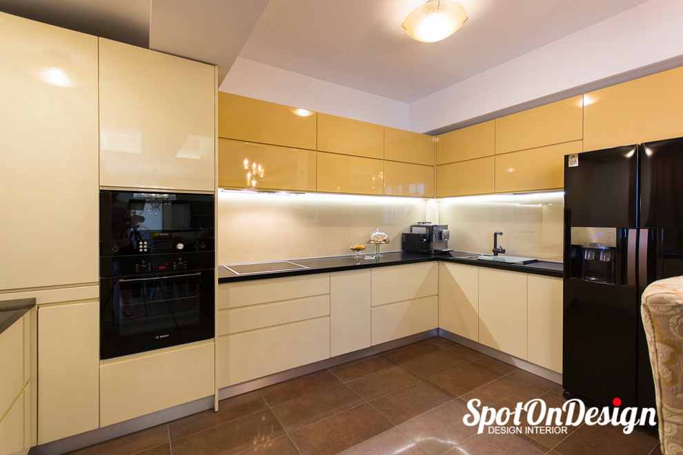 Design ideas for a mid-sized eclectic u-shaped eat-in kitchen in Other with a drop-in sink, flat-panel cabinets, laminate benchtops, glass sheet splashback, black appliances, ceramic floors, yellow cabinets and yellow splashback.