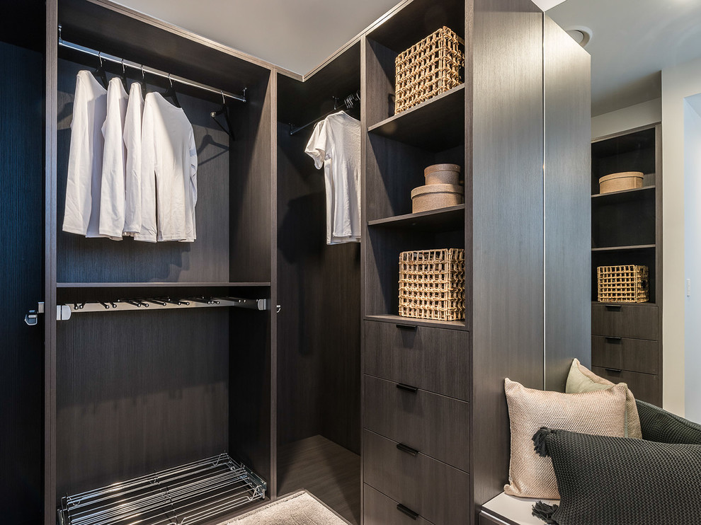Contemporary gender-neutral walk-in wardrobe in Brisbane with flat-panel cabinets, dark wood cabinets, dark hardwood floors and beige floor.