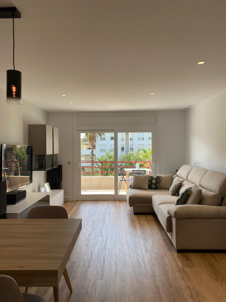 This is an example of a large contemporary open concept living room in Barcelona with laminate floors and a wall-mounted tv.