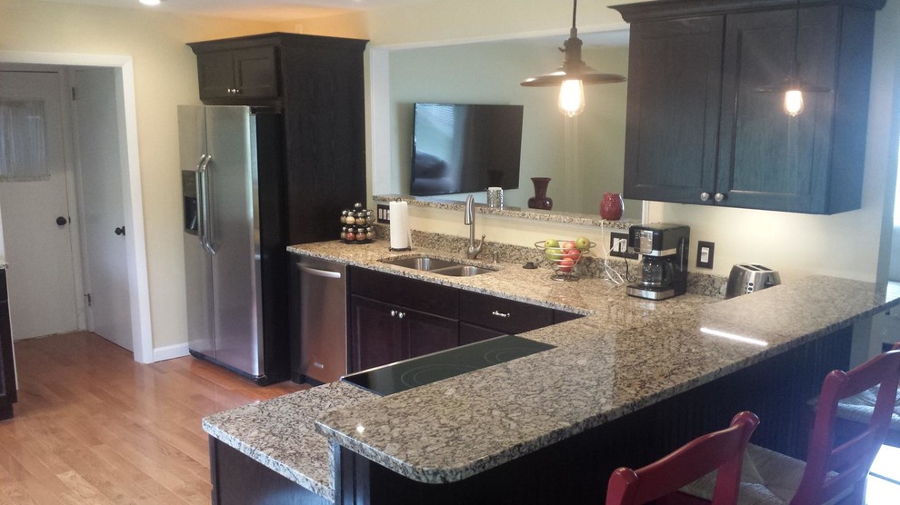 Inspiration for a large transitional l-shaped light wood floor and brown floor eat-in kitchen remodel with a double-bowl sink, recessed-panel cabinets, black cabinets, granite countertops, stainless steel appliances, an island and gray countertops