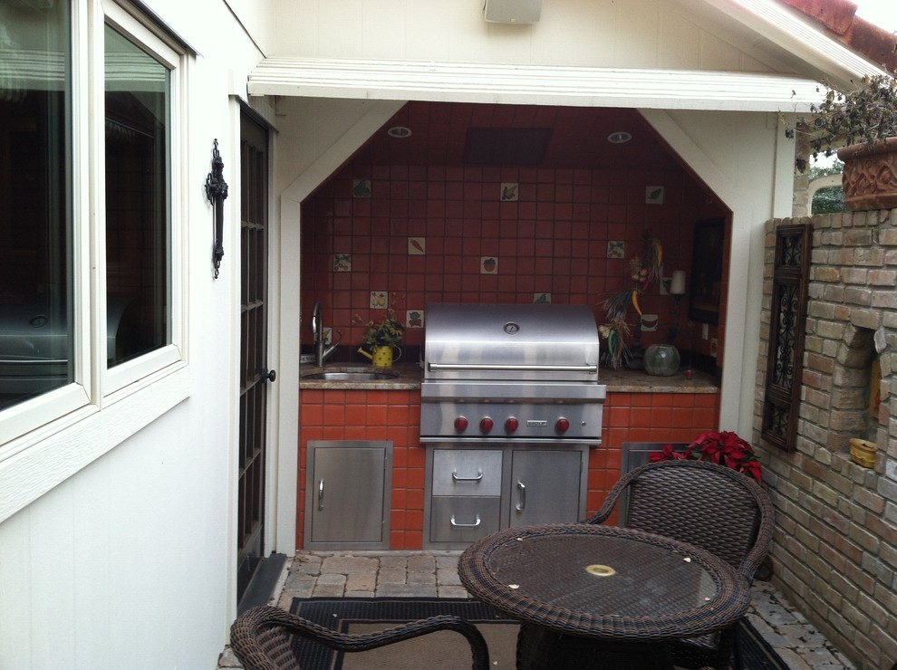 Photo of a small mediterranean courtyard patio in Austin with an outdoor kitchen, brick pavers and a roof extension.