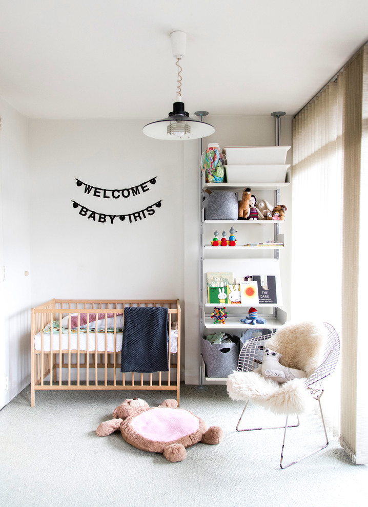 Photo of a small contemporary gender-neutral nursery in London with white walls, carpet and grey floor.