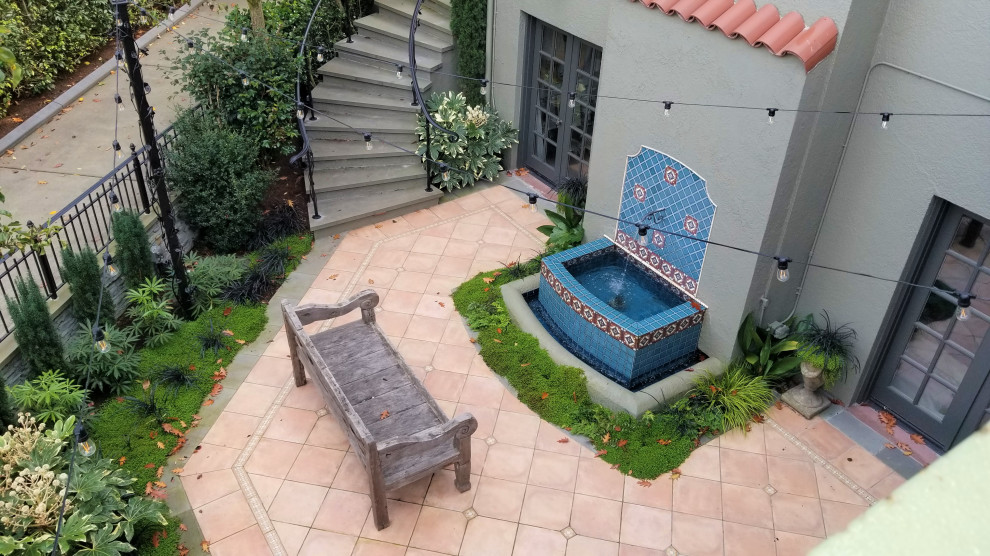 Imagen de patio mediterráneo en patio trasero con adoquines de hormigón