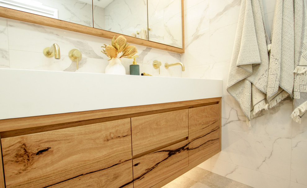 Mid-sized contemporary master bathroom in Sydney with medium wood cabinets, a drop-in tub, a shower/bathtub combo, a one-piece toilet, an integrated sink, a hinged shower door, white benchtops, a niche, a double vanity and a floating vanity.