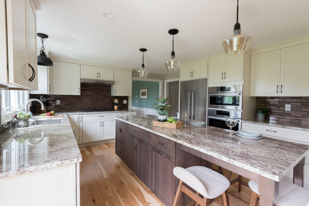 Inspiration for a mid-sized transitional u-shaped light wood floor and brown floor eat-in kitchen remodel in Boston with an undermount sink, shaker cabinets, white cabinets, granite countertops, brown backsplash, glass tile backsplash, stainless steel appliances, an island and multicolored countertops