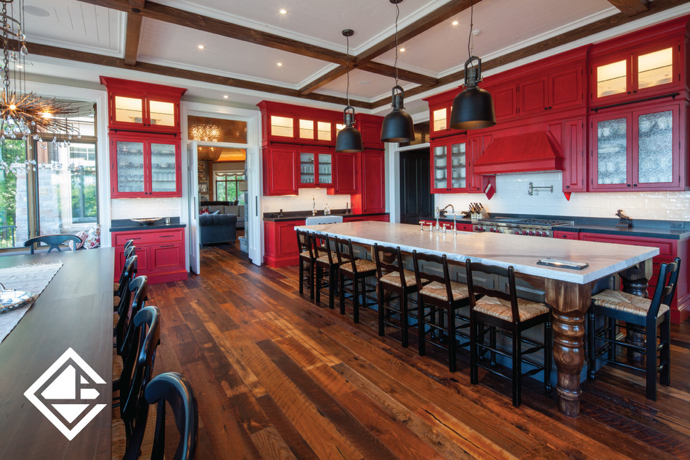 Eat-in kitchen - huge rustic l-shaped medium tone wood floor eat-in kitchen idea with a farmhouse sink, raised-panel cabinets, red cabinets, granite countertops, white backsplash, stainless steel appliances and an island