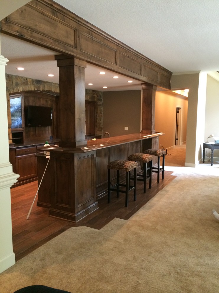 Photo of a mid-sized traditional galley wet bar in Kansas City with dark wood cabinets, timber splashback and dark hardwood floors.
