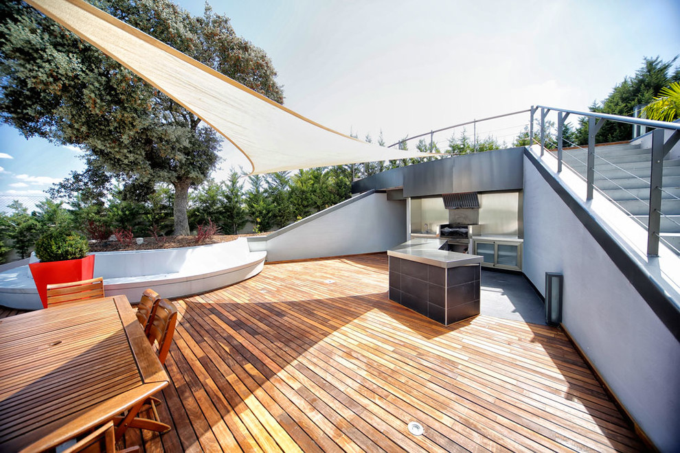 Design ideas for a large contemporary backyard deck in Madrid with an awning.