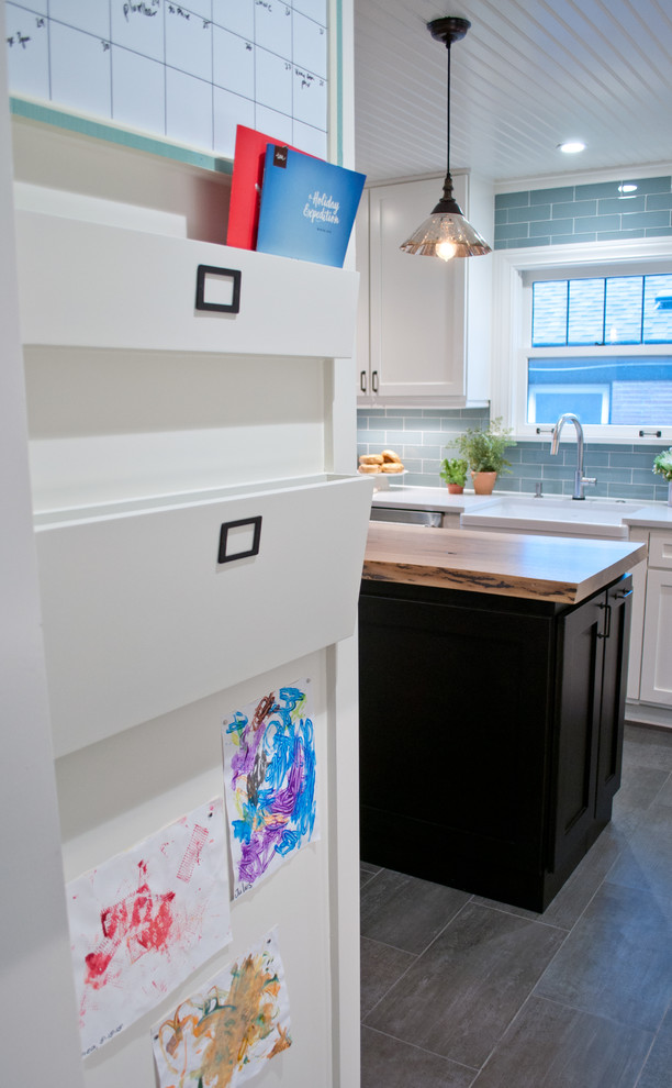 This is an example of a small transitional u-shaped separate kitchen in Seattle with a farmhouse sink, shaker cabinets, white cabinets, quartzite benchtops, blue splashback, glass tile splashback, stainless steel appliances, porcelain floors, with island and grey floor.