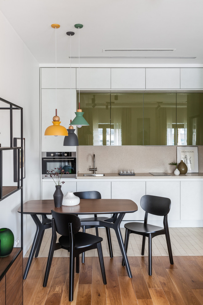 Photo of a small scandinavian single-wall eat-in kitchen in Moscow with an undermount sink, flat-panel cabinets, white cabinets, solid surface benchtops, beige splashback, stainless steel appliances, porcelain floors, no island, beige floor and beige benchtop.