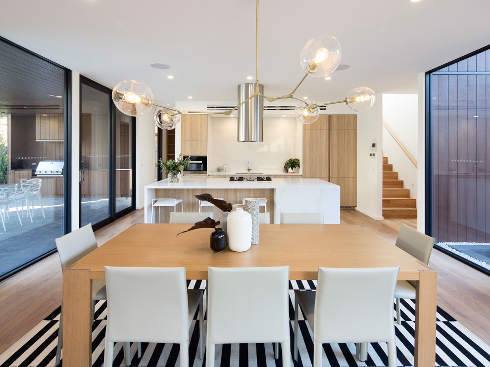 Inspiration for a contemporary kitchen/dining combo in Melbourne with white walls, medium hardwood floors and brown floor.