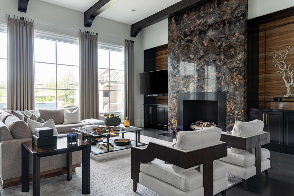 Design ideas for a large mediterranean open concept family room in Dallas with multi-coloured walls, dark hardwood floors, a standard fireplace, a stone fireplace surround, a wall-mounted tv and black floor.