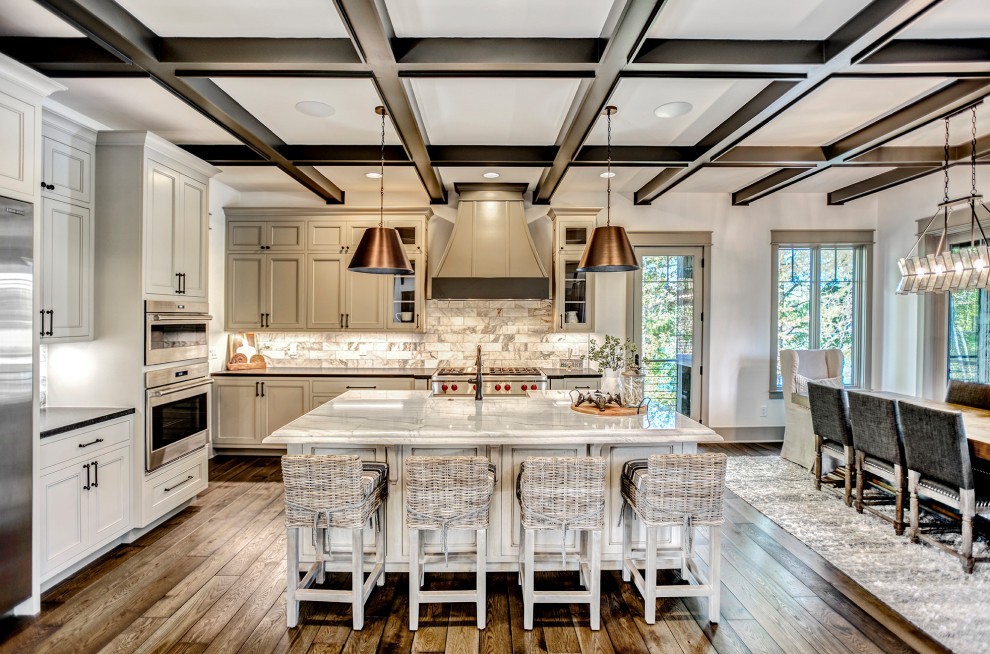 Bild på ett stort vintage vit vitt kök, med en rustik diskho, luckor med infälld panel, vita skåp, granitbänkskiva, flerfärgad stänkskydd, stänkskydd i stenkakel, rostfria vitvaror, mellanmörkt trägolv, en köksö och brunt golv