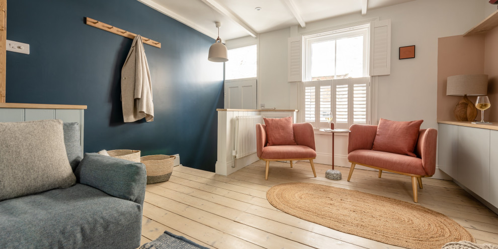 На фото: маленькая открытая гостиная комната в скандинавском стиле с синими стенами, светлым паркетным полом, стандартным камином, фасадом камина из металла, отдельно стоящим телевизором, балками на потолке и акцентной стеной для на участке и в саду с