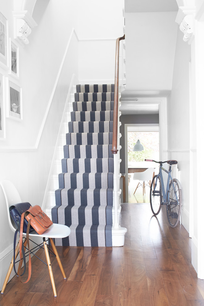 This is an example of a transitional painted wood u-shaped staircase in London with painted wood risers.