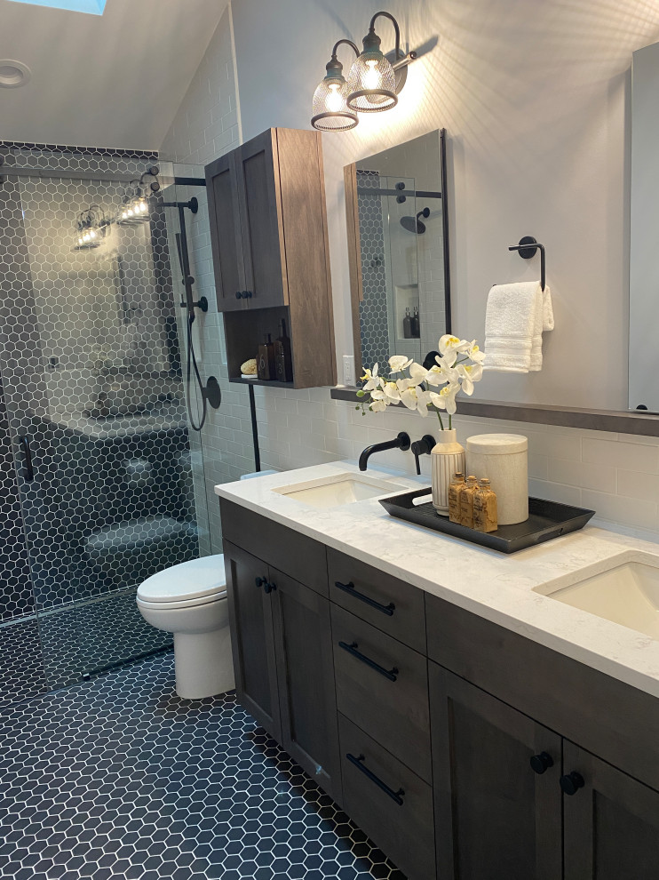 This is an example of a mid-sized contemporary master bathroom in Seattle with shaker cabinets, brown cabinets, a curbless shower, black tile, grey walls, pebble tile floors, an undermount sink, engineered quartz benchtops, black floor, a sliding shower screen, beige benchtops, a niche, a double vanity, a built-in vanity and vaulted.