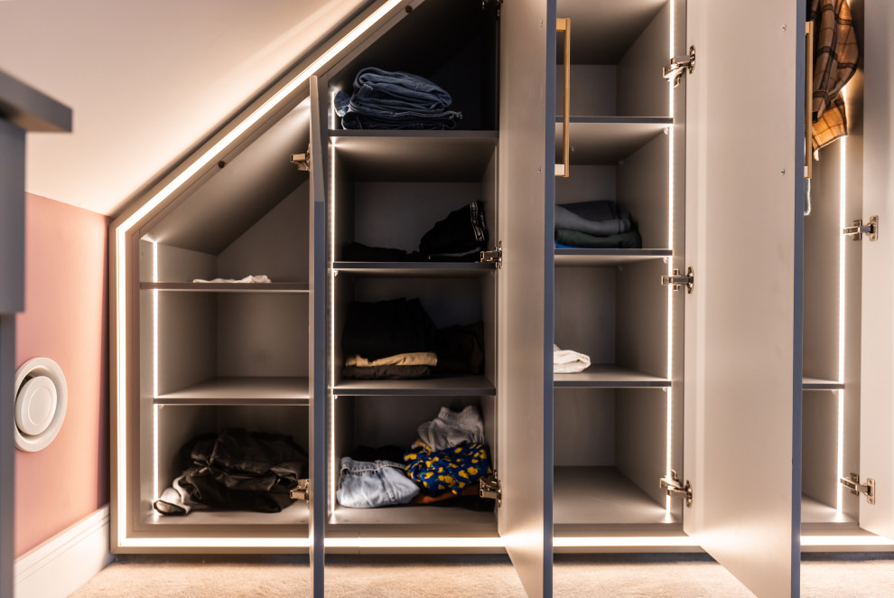 Inspiration for a mid-sized contemporary gender-neutral storage and wardrobe in Buckinghamshire with shaker cabinets, grey cabinets, carpet and beige floor.