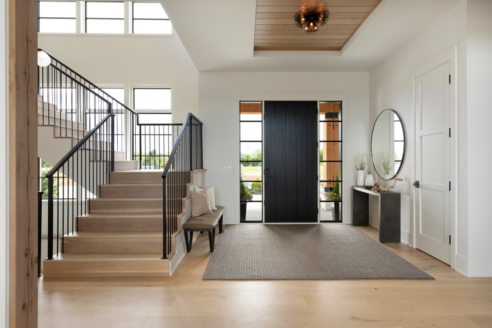 Idéer för en klassisk entré, med vita väggar, ljust trägolv, en enkeldörr, en svart dörr och brunt golv