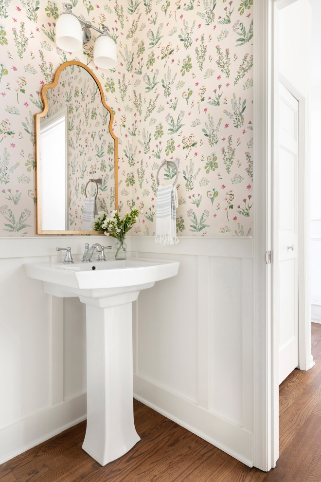 Design ideas for a transitional powder room in Minneapolis with multi-coloured walls, medium hardwood floors, a pedestal sink, brown floor, decorative wall panelling and wallpaper.