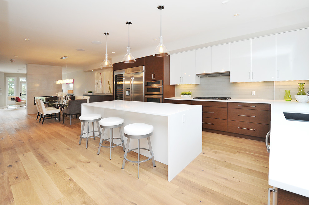 Large transitional l-shaped medium tone wood floor eat-in kitchen photo in Calgary with an undermount sink, flat-panel cabinets, medium tone wood cabinets, gray backsplash, stainless steel appliances and an island