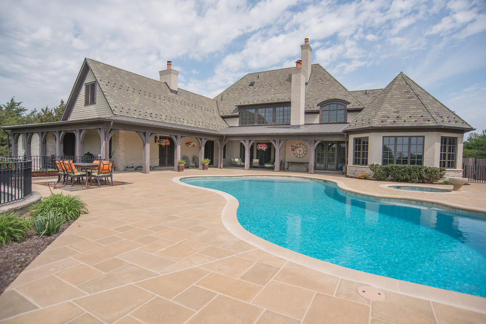 This is an example of a mid-sized country backyard custom-shaped pool in Other with a hot tub and concrete pavers.